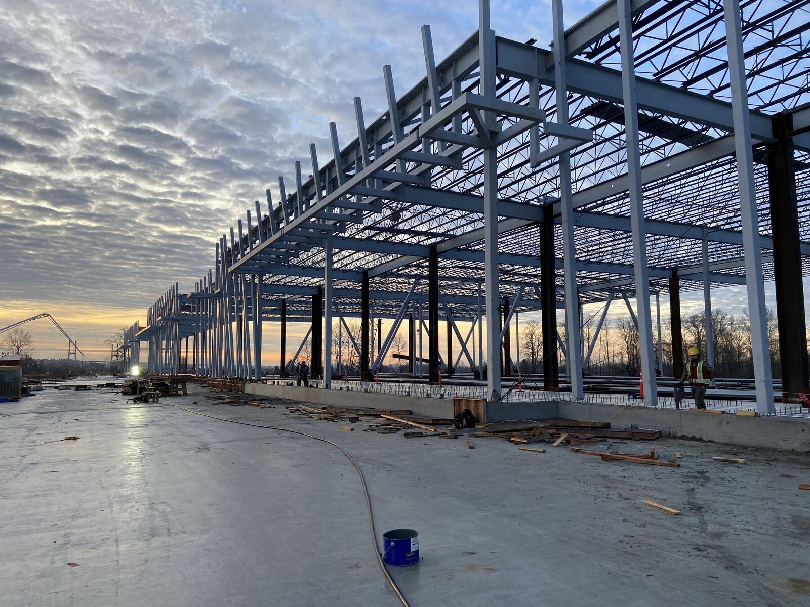 Structural steel columns, joists and roof deck going up on a large-format industrial building at dawn